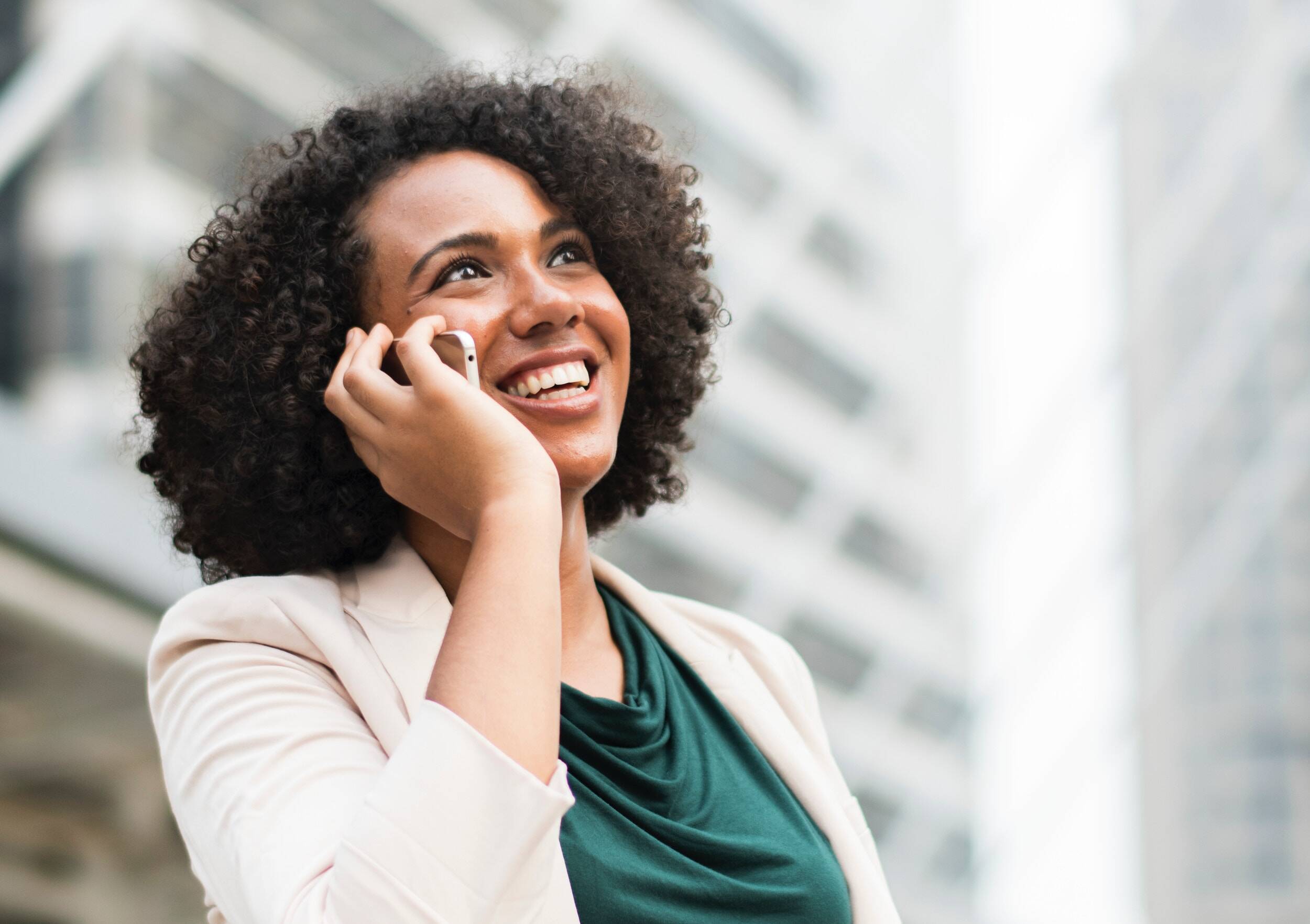 woman using telephone standing near building